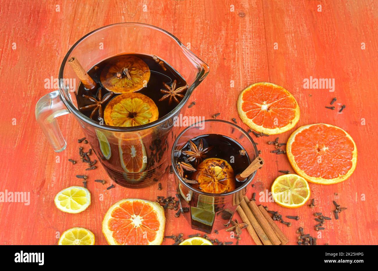 Drink invernale caldo di Natale o di Capodanno, cocktail piccante alle grog, sangria o VIN brulé con tè, limone, rum, cannella, anice. Stile rustico. Natale VIN brulé in un bicchiere su un tavolo rustico in legno Foto Stock