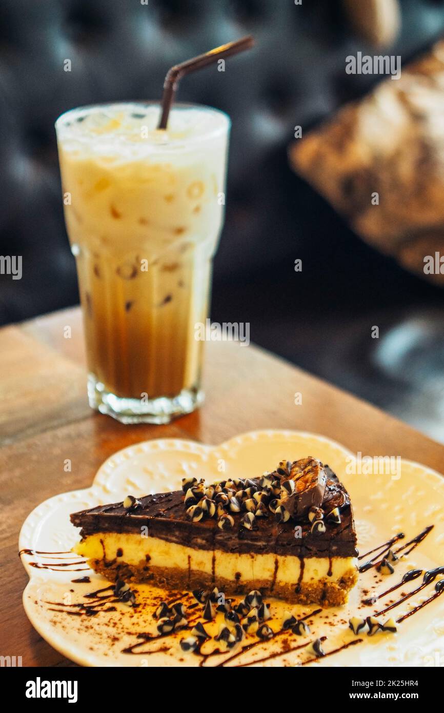 Un vetrino di torta al cioccolato con caffè latte ghiacciato in un bicchiere alto. Freddo sfondo estivo Foto Stock