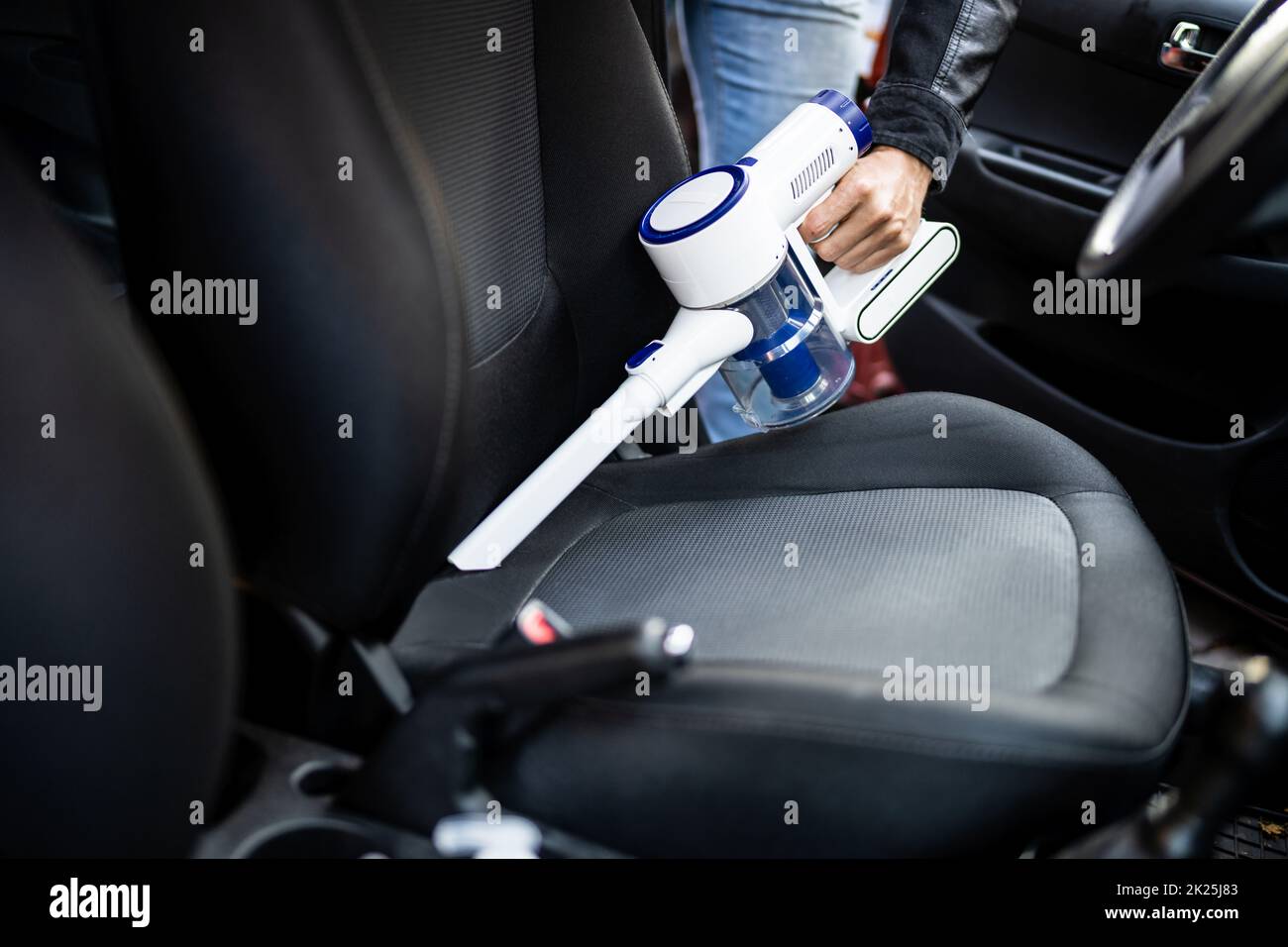 Pulizia degli interni dei sedili per auto con aspirapolvere portatile Foto Stock