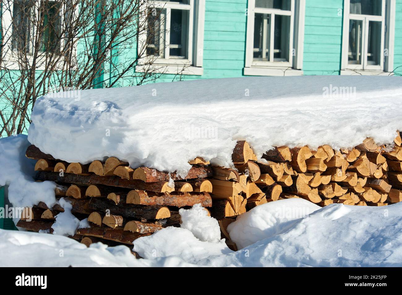 Legno accatastato in un palo di legno sotto la neve in inverno Foto Stock