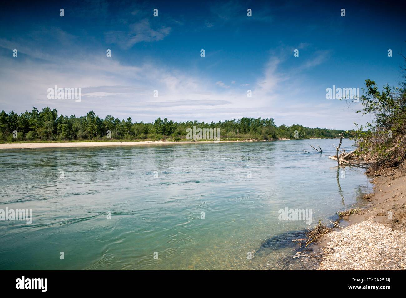 Un bellissimo scatto di un lago riflettente in un paesaggio verde su uno sfondo blu cielo Foto Stock