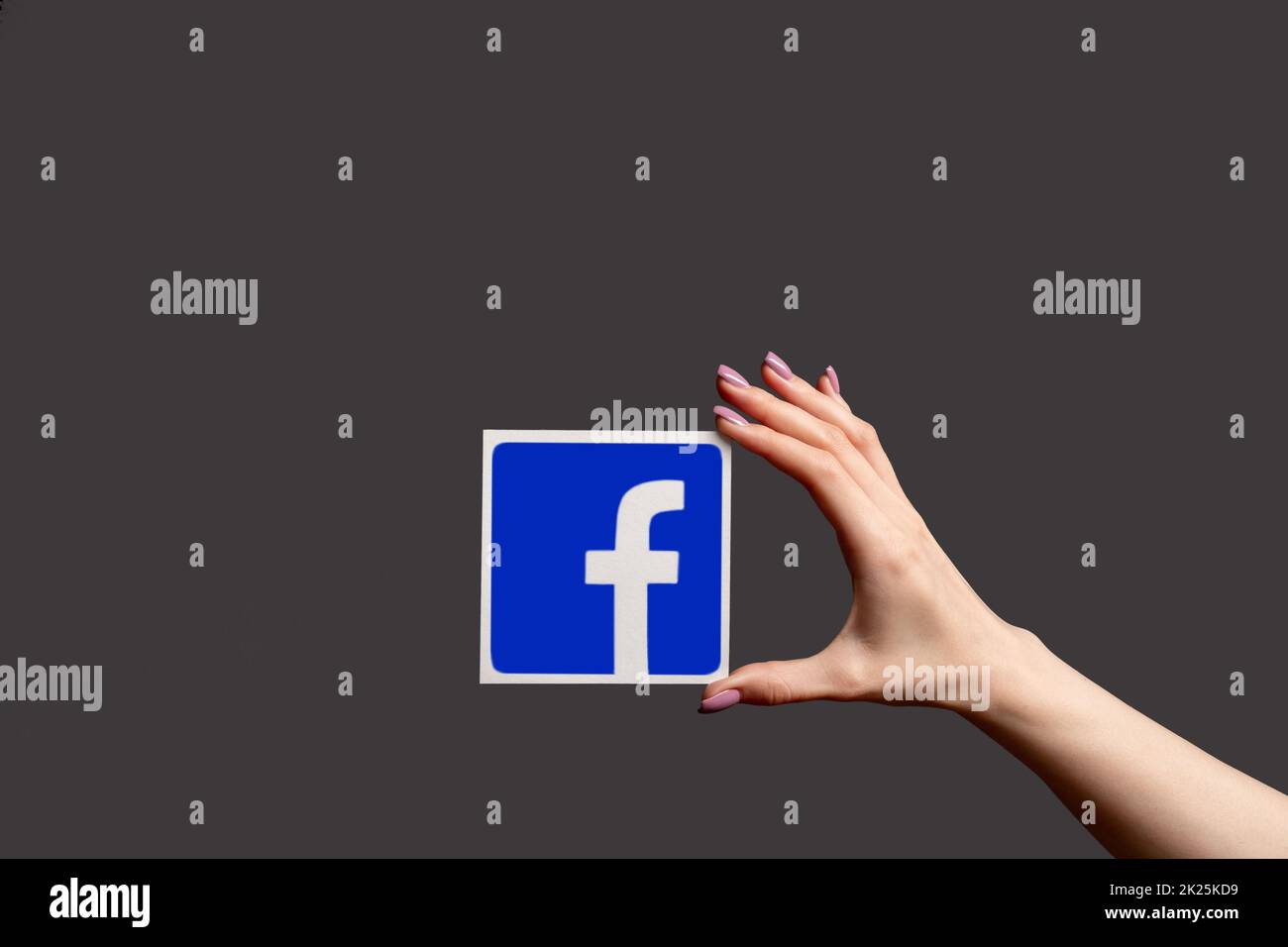 Kharkiv, Ucraina - 05 giugno 2020: Logo Facebook. Segui i social media. Promozione del sito Web. Mano donna che presenta il simbolo dell'icona dell'app mobile isolato al buio g Foto Stock