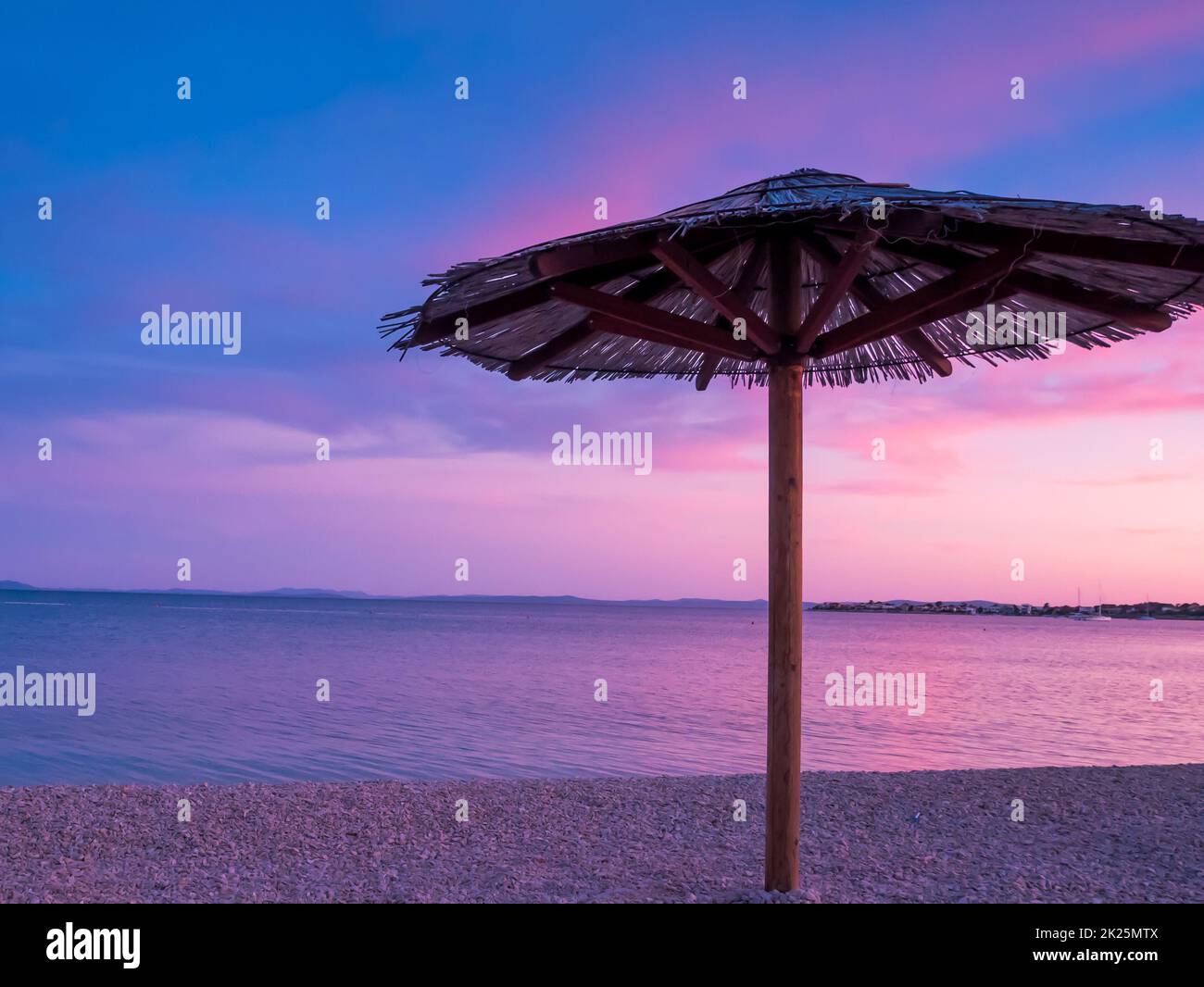 Vista del bellissimo tramonto blu e viola, cielo e ombrellone di paglia Foto Stock