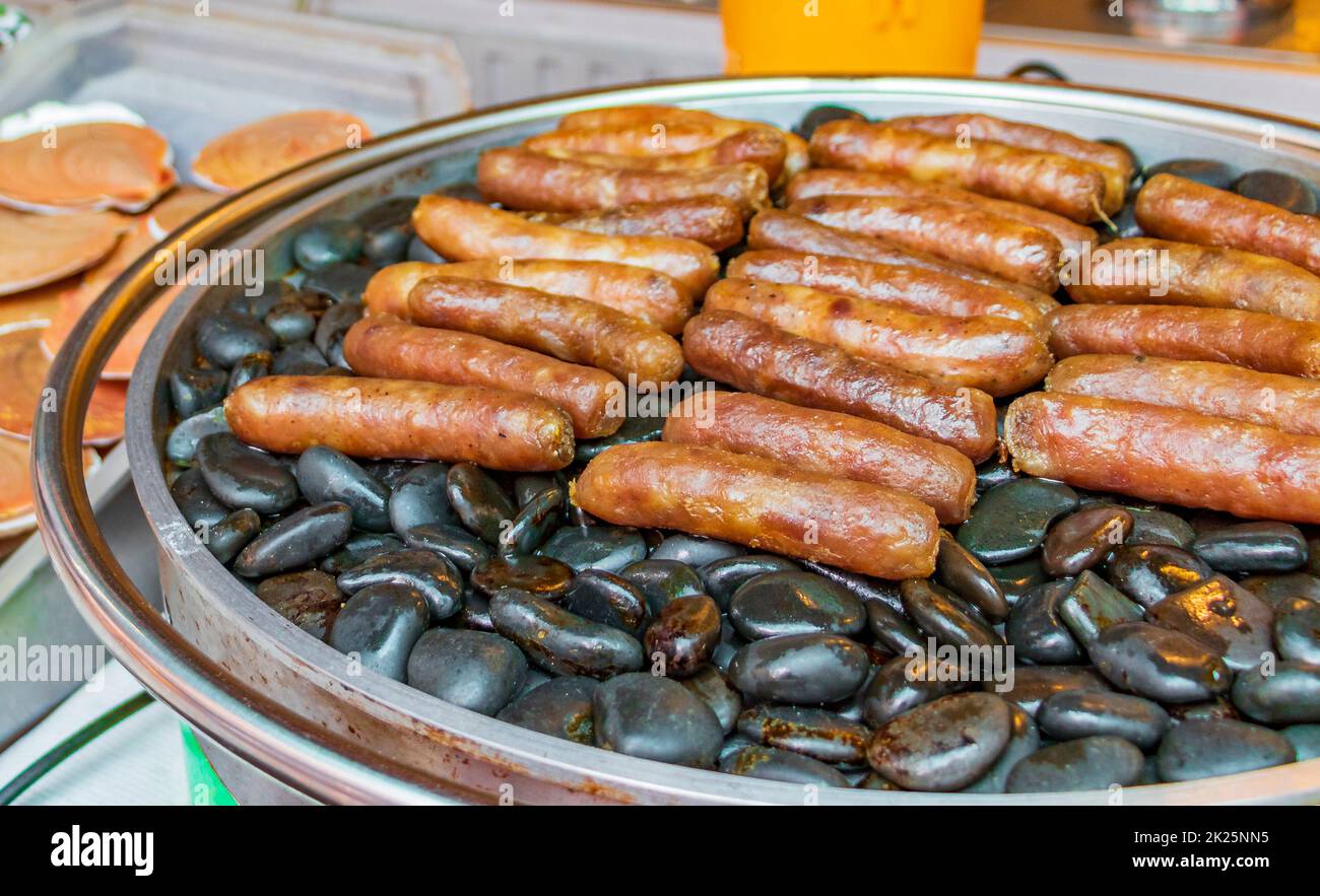 Salsicce alla griglia su pietre calde mercato tailandese China Town Bangkok. Foto Stock