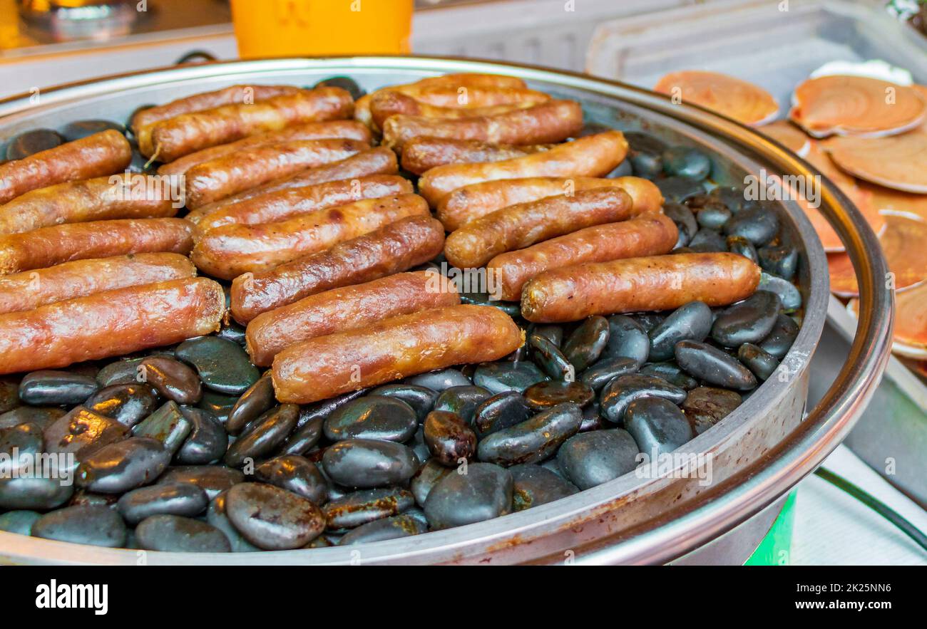 Salsicce alla griglia su pietre calde mercato tailandese China Town Bangkok. Foto Stock