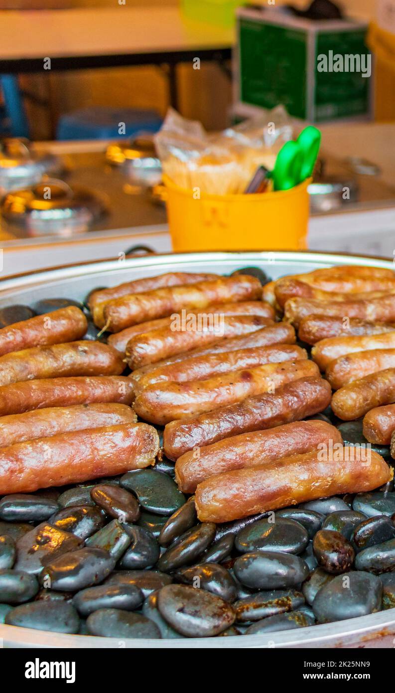 Salsicce alla griglia su pietre calde mercato tailandese China Town Bangkok. Foto Stock