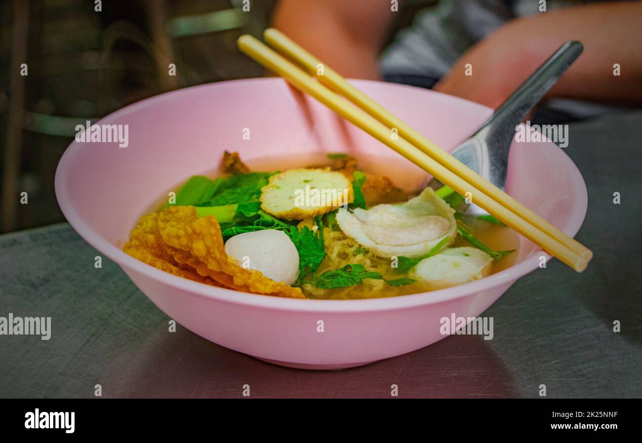 Zuppa di noodle tailandese con palle di pesce ciotola rosa chopsticks Thailandia. Foto Stock