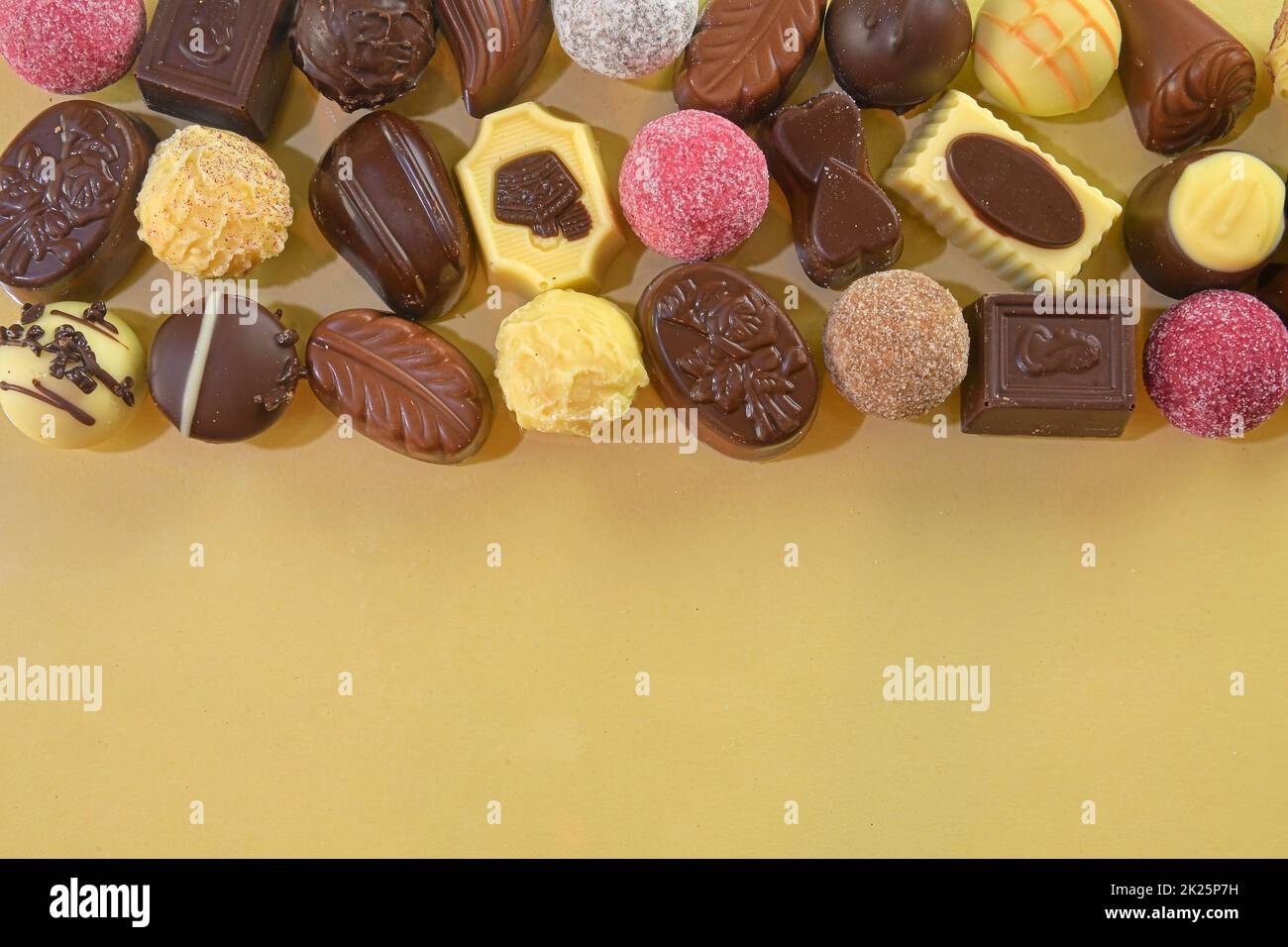 Biscotti al cioccolato e praline per un evento di vacanza su sfondo dorato con ampio spazio per copie. Disposizione piatta Foto Stock