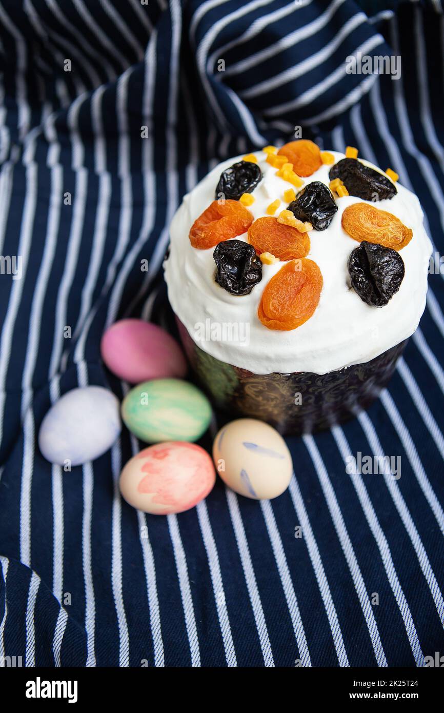 Uova di Pasqua decorate con acquerelli e torta di Pasqua giacciono su un grembiule blu a strisce. Concetto di vacanza religiosa di Pasqua, vista dall'alto. Foto Stock