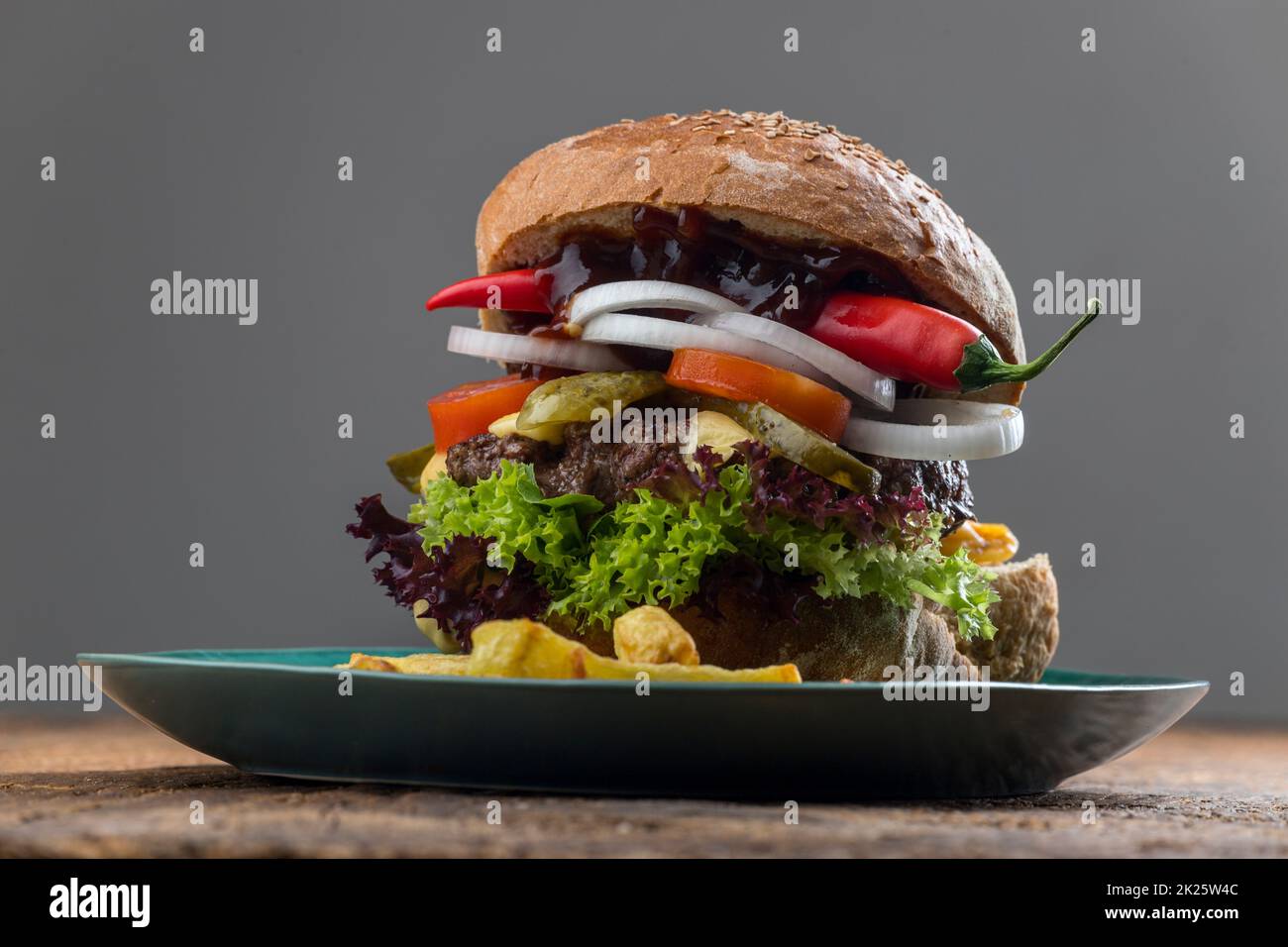 cheeseburger su un piatto blu con peperoncino Foto Stock