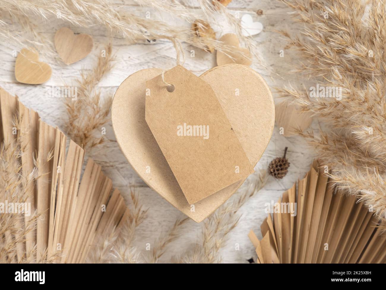 San Valentino a forma di cuore presente con etichetta regalo vuota, erba di pampas e cuori, boho Mockup Foto Stock