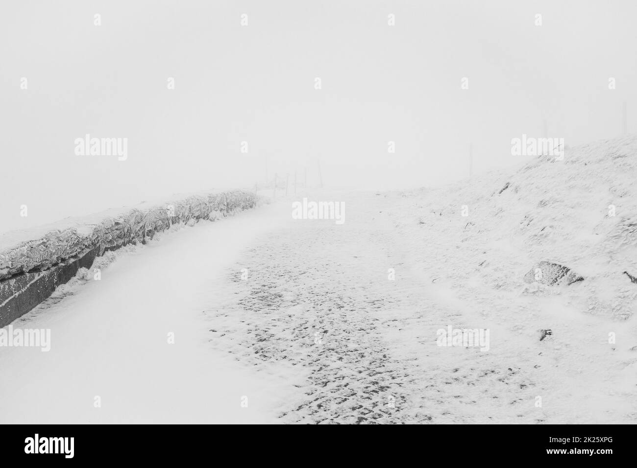 Strada invernale in salita in cattive condizioni meteorologiche. Paesaggio invernale. Foto Stock