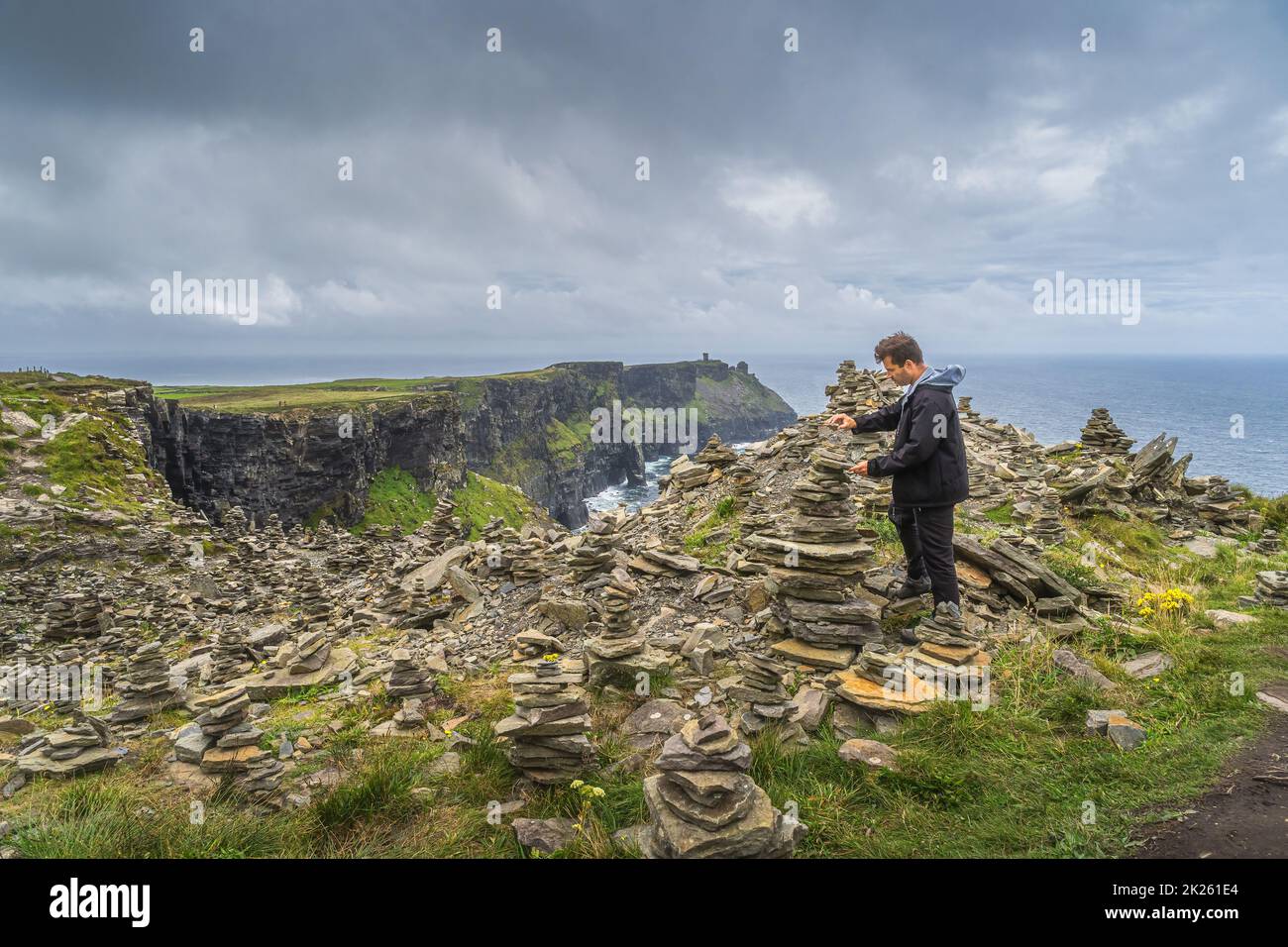 Uomo impilamento di pietra nelle iconiche scogliere di Moher, Irlanda Foto Stock