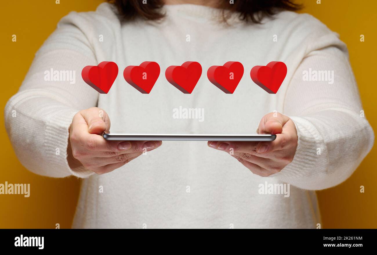la donna tiene una tavoletta elettronica e cinque cuori rossi sopra di essa. Concetto di feedback, valutazione aziendale Foto Stock