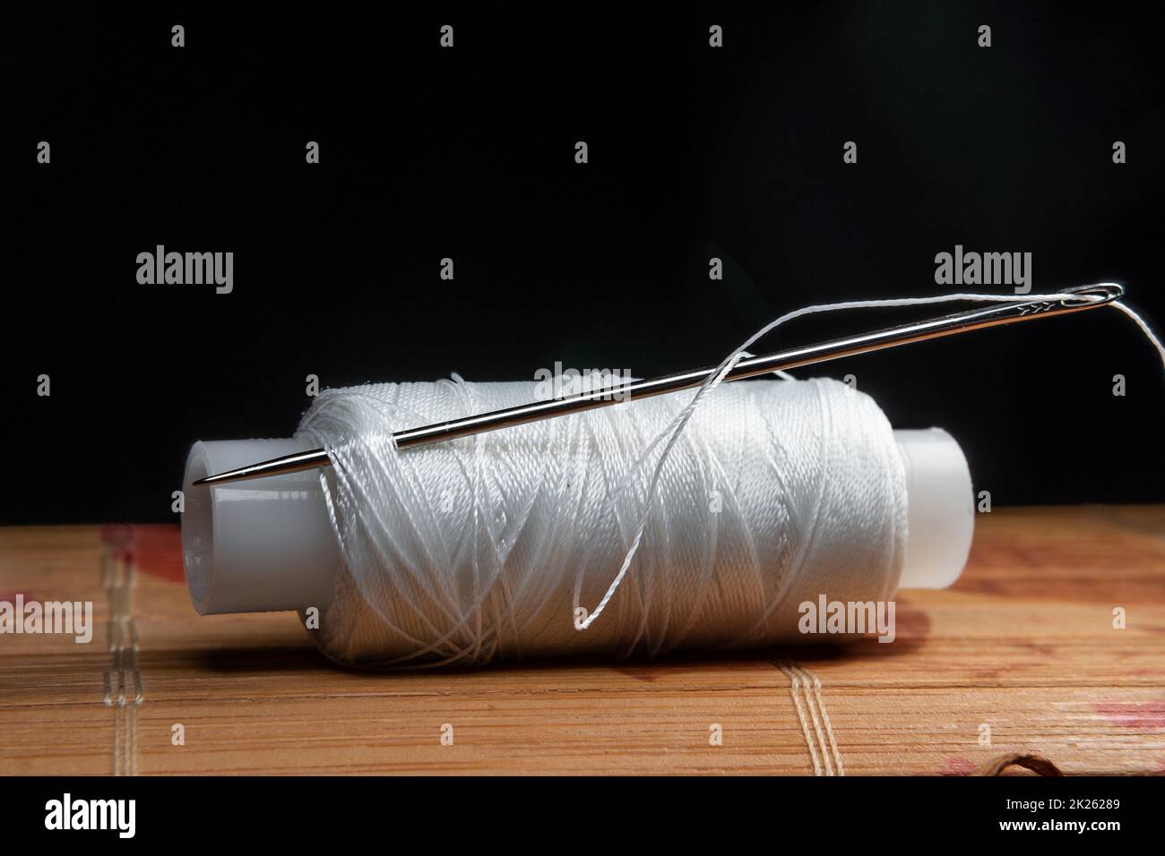 Il filo è filettato attraverso l'occhio di un ago da cucire.cucire e cucire classi.Workshop di artigianato e artigianale.luogo di lavoro dell'industria tessile.l'ago da ricamo è bloccato in una bobina Foto Stock