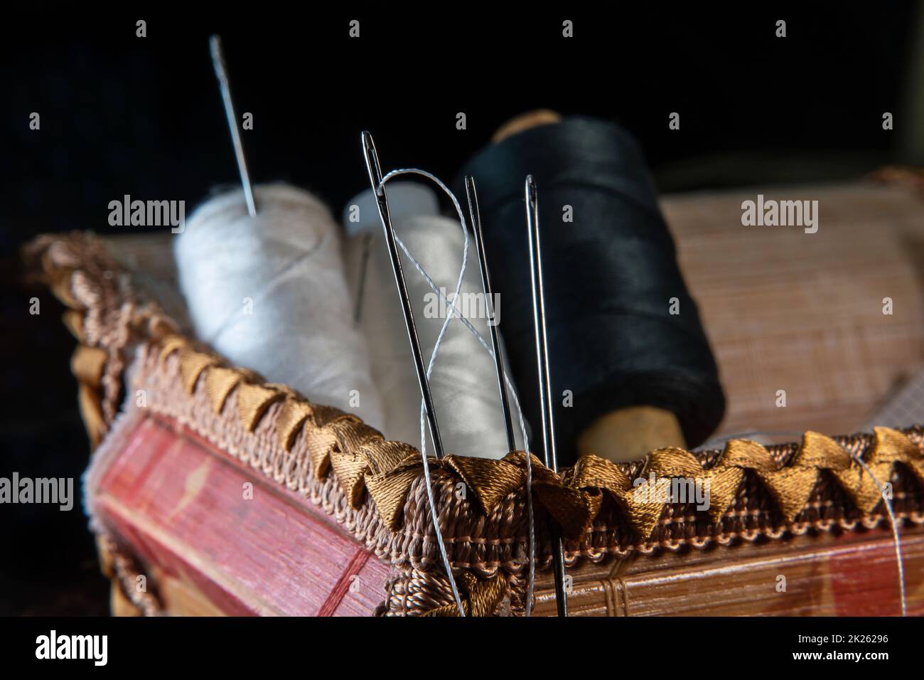 Il filo è filettato attraverso l'occhio di un ago da cucire.cucire e cucire classi.Workshop di artigianato e artigianale.luogo di lavoro dell'industria tessile.l'ago da ricamo è bloccato in una bobina Foto Stock