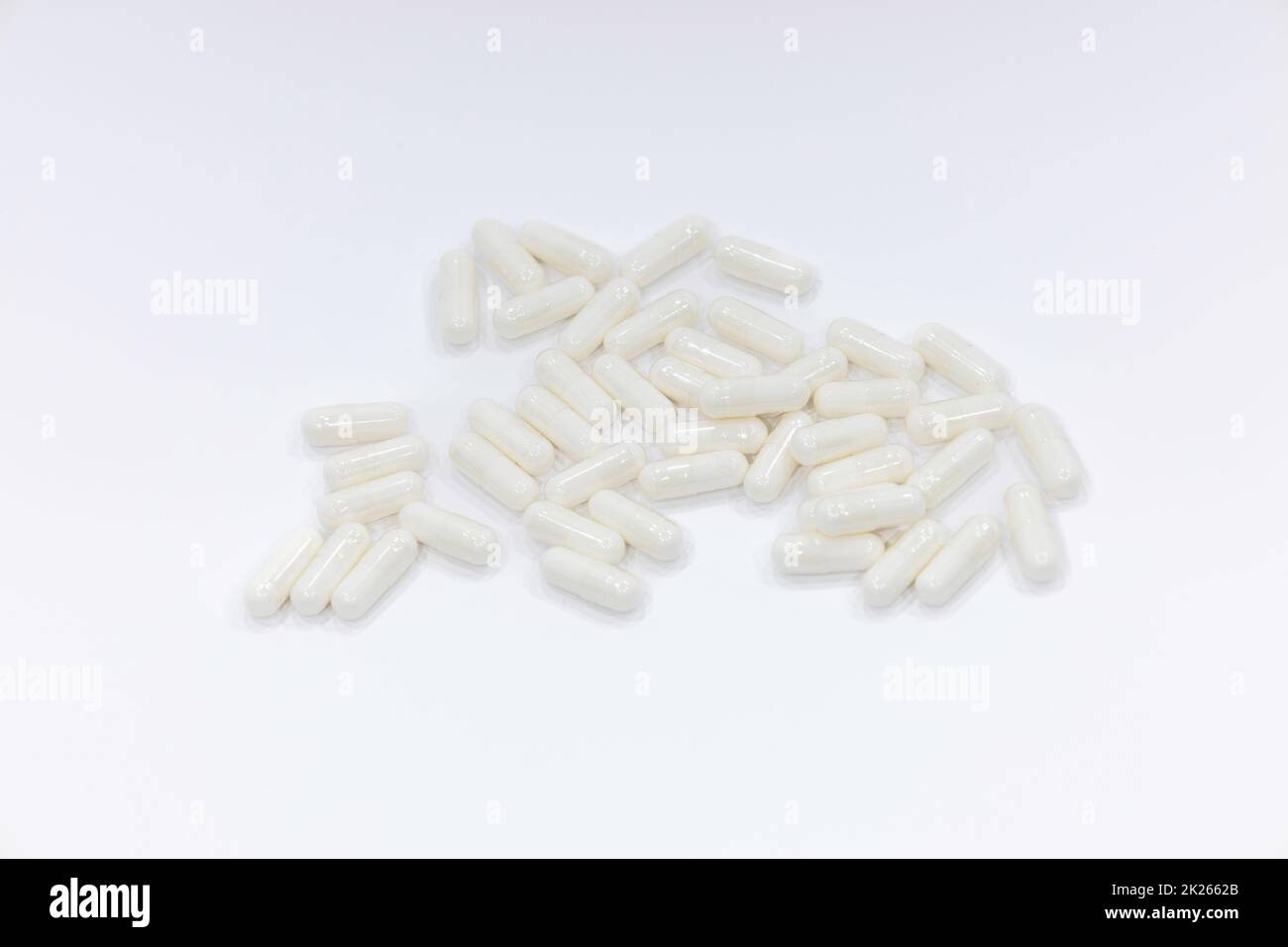 Primo piano di una pila di capsule bianche. Farmaci su sfondo bianco Foto Stock