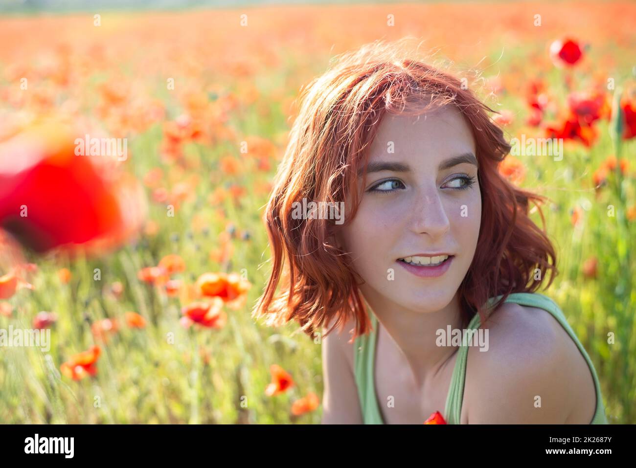 ragazza giovane felice con capelli rossi in campo papavero Foto Stock