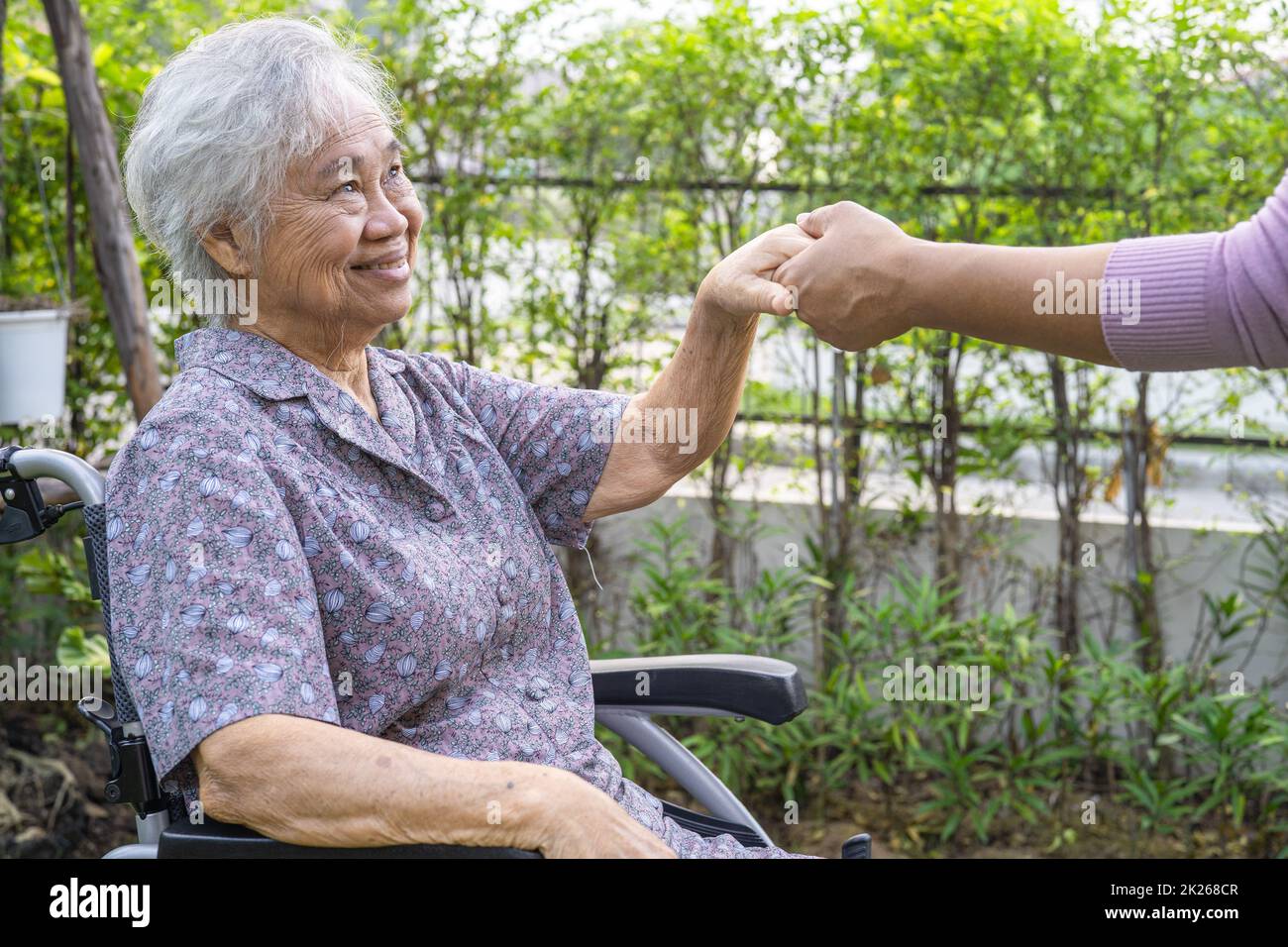 Tenere le mani Asian anziano o anziano donna anziana paziente con amore, cura, incoraggiare e empatia al parco. Foto Stock