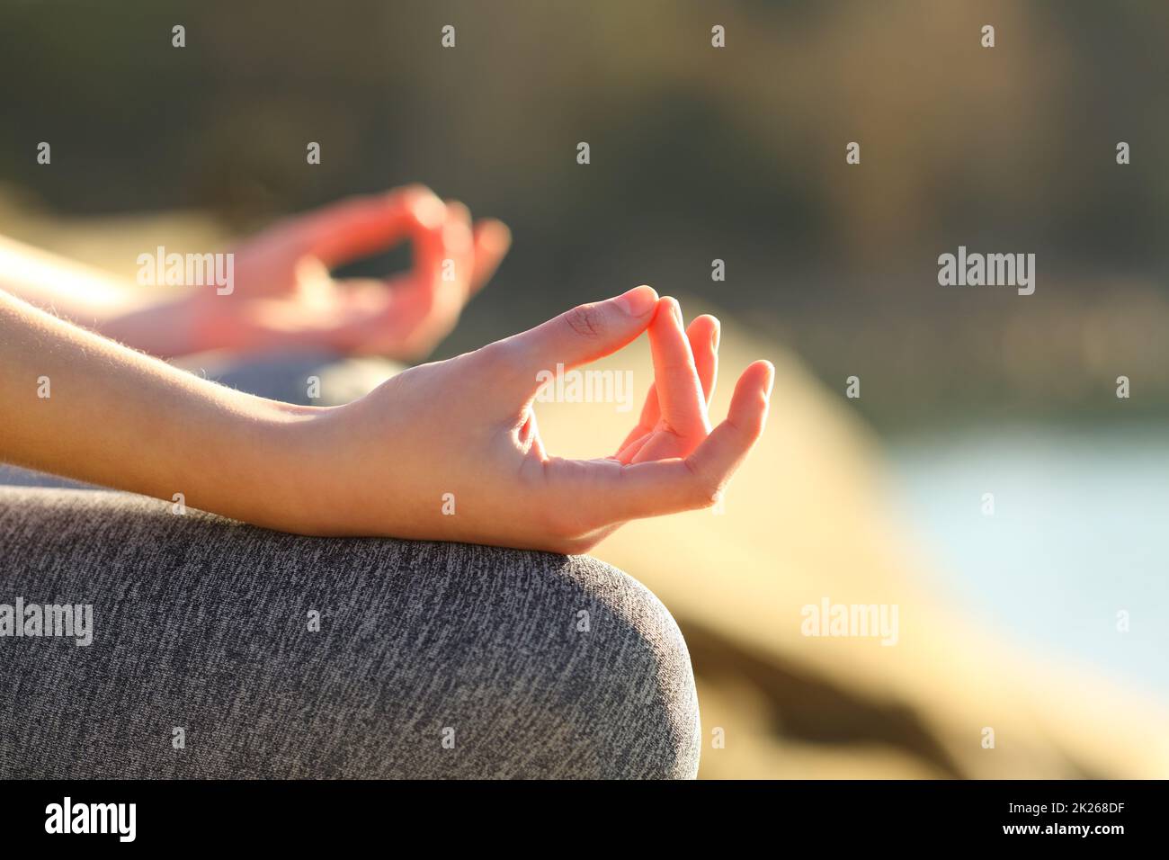 Mani di donna che fanno l'esercitazione di yoga in un lago Foto Stock