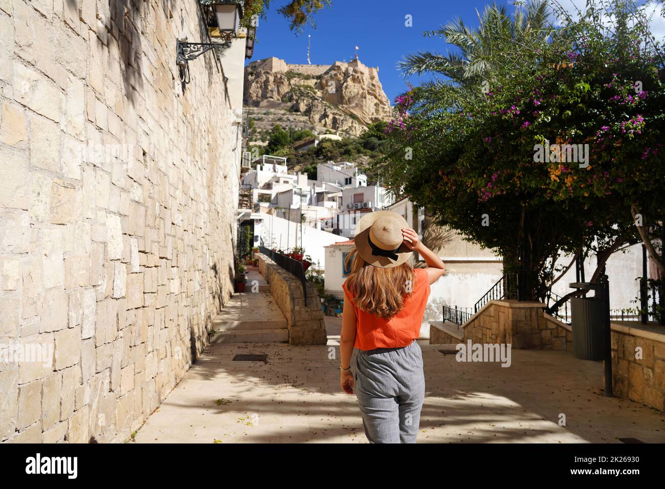 Esplorare Alicante in Spagna. Giovane donna viaggiatore che cammina nel quartiere di Santa Cruz guardando il Monte Benacantil con il castello di Santa Barbara ad Alicante, Spagna. Foto Stock