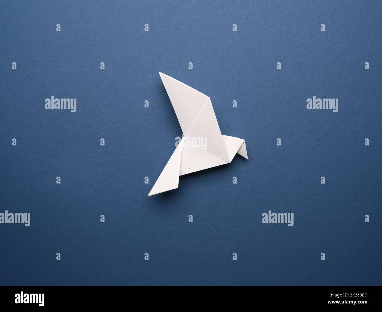 Piccione origami bianco su sfondo di carta blu Foto Stock