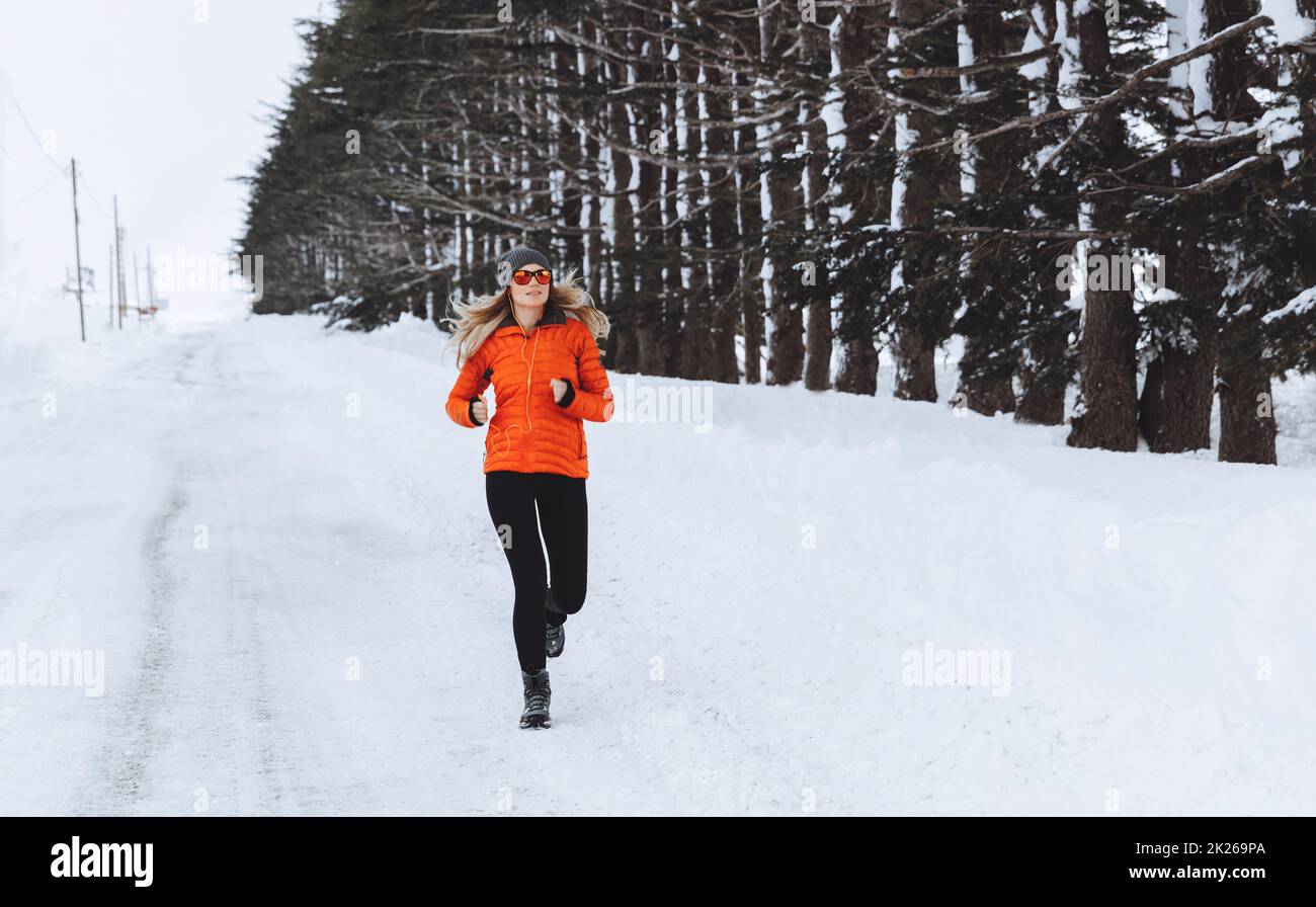 Donna che corre nella foresta d'inverno Foto Stock