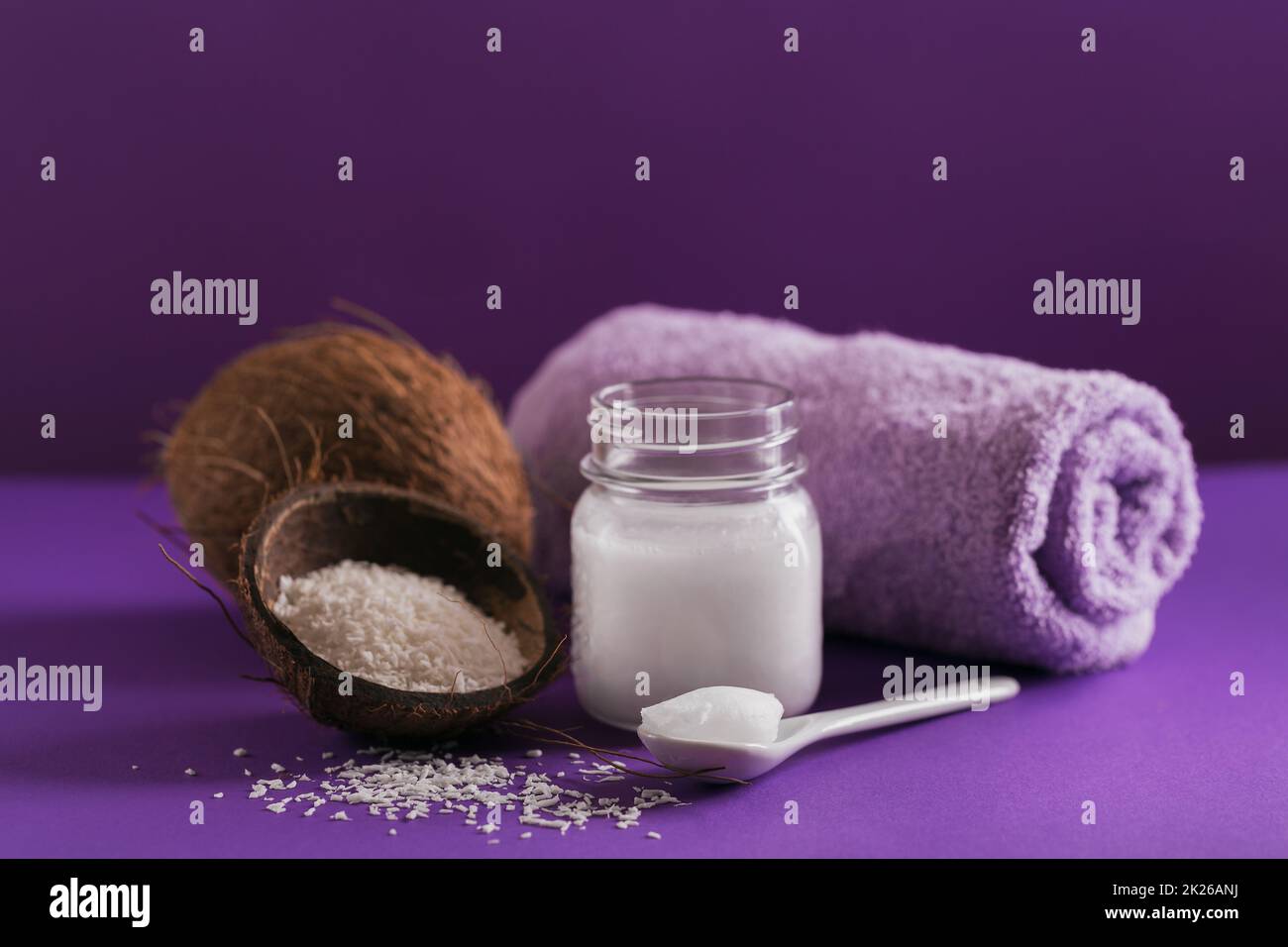 Composizione con crema corpo cosmetica naturale di olio di cocco organico su fondo di colore viola Foto Stock