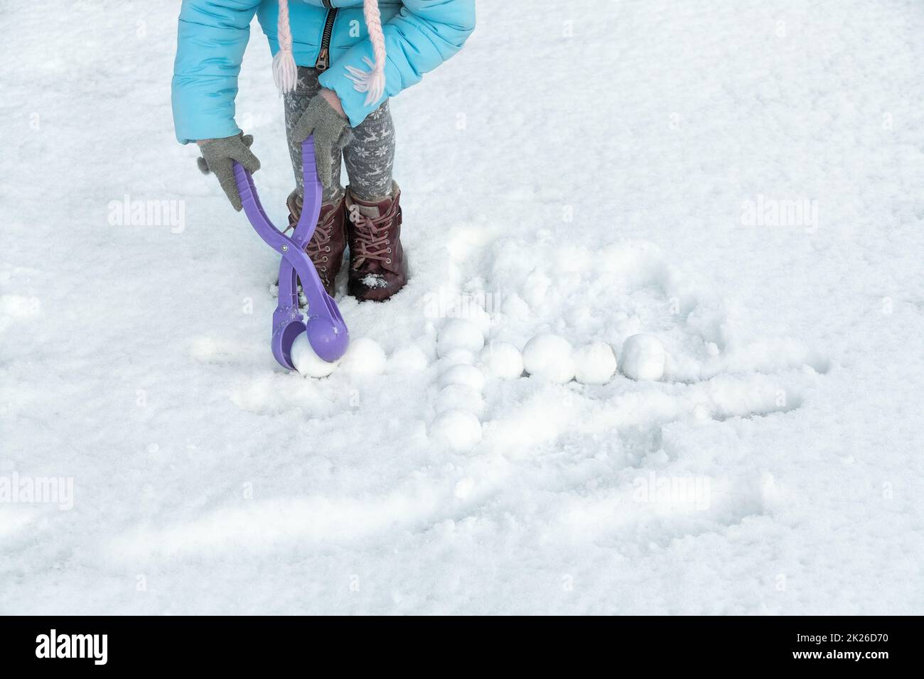 I bambini si divertono a fare palle di neve con un macchinista di plastica giocattolo. Bambini che giocano a palle di neve tra le nevicate. Posiziona per testo. Foto Stock