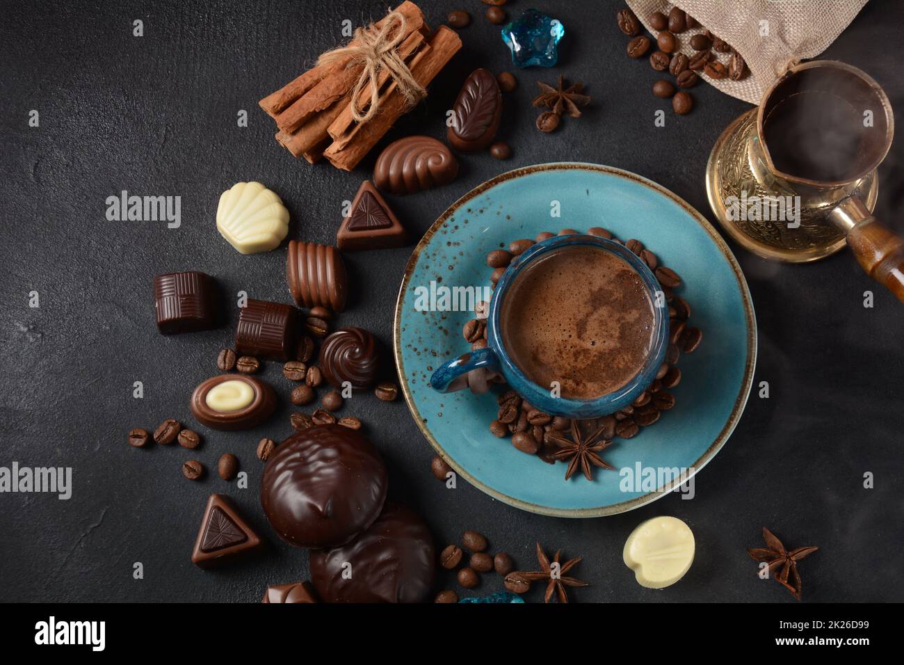 Tazza di caffè, fagioli, cioccolato su vecchio tavolo da cucina assortimento di dolci al cioccolato fondente, bianco e latte, zefiro (zephyr). Spezie, cannella. Foto Stock