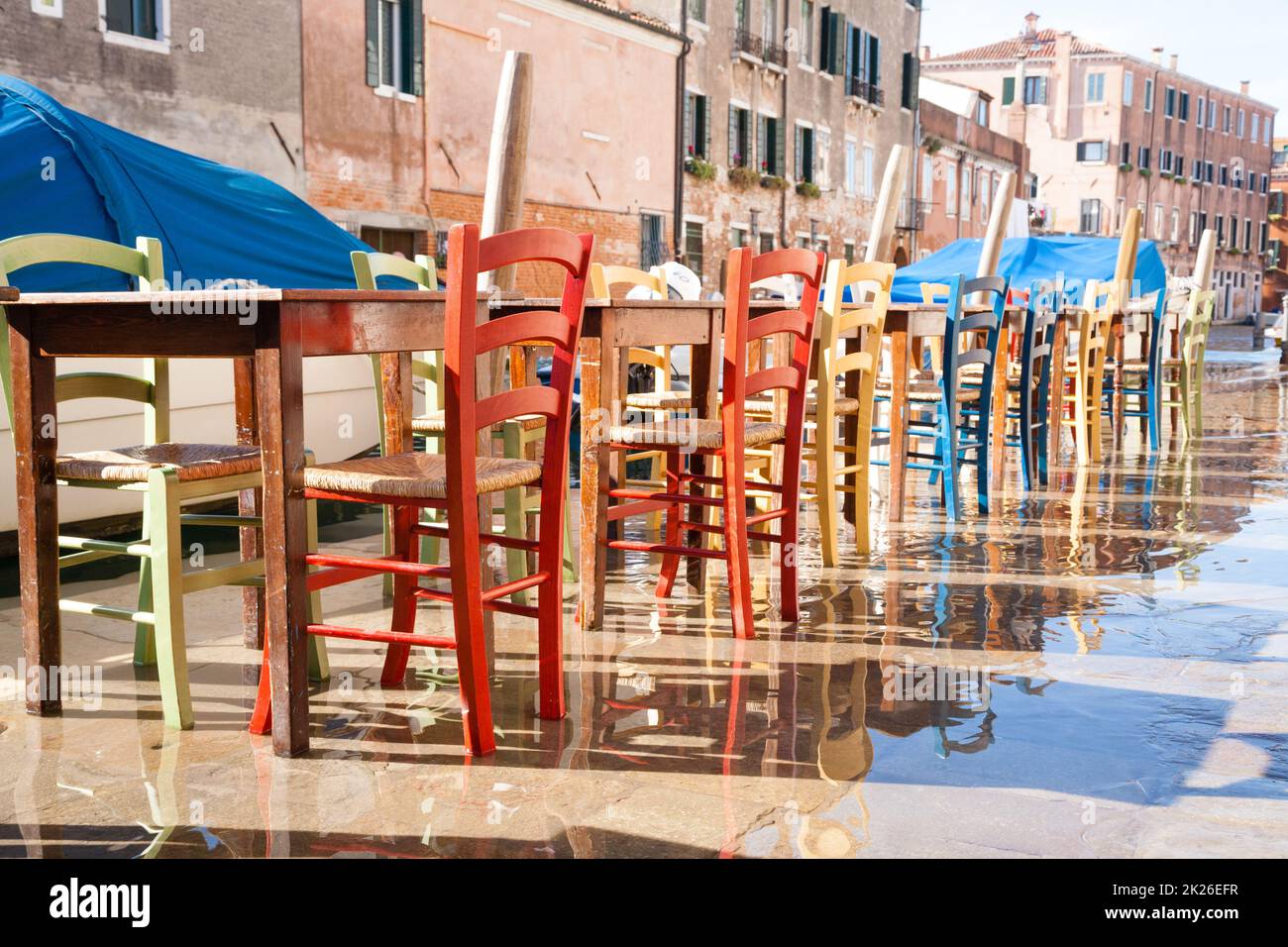 Sedie colorate in fila lungo il canale veneziano Foto Stock