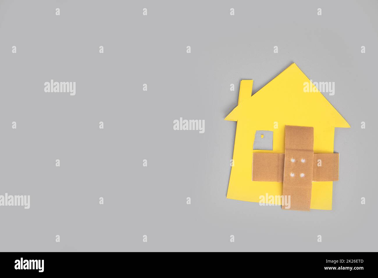 Primo piano di casa spezzata figura con banda incrociata aiuto su sfondo grigio vista dall'alto, copia spazio, divorzio, problemi di relazione, casa in movimento, ipoteca Foto Stock