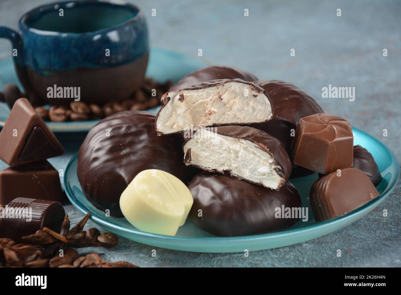 Zefir (zephyr), tazza di caffè, fagioli, cioccolato su tavola assortimento di dolci scuri, bianchi e al cioccolato al latte. Foto Stock