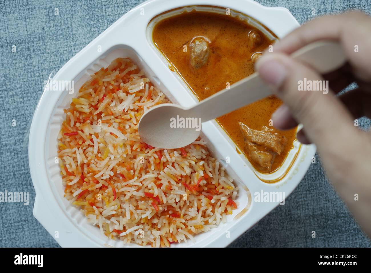 pollo al curry e riso in una confezione di plastica da portare via sul tavolo Foto Stock