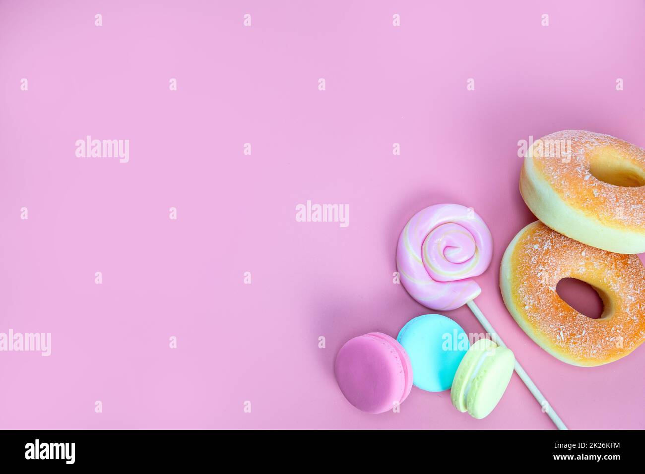 Dolce caramelle concetto. Lecca e ciambelle rosa, macaron su sfondo rosa, vista dall'alto dello spazio di copia Foto Stock