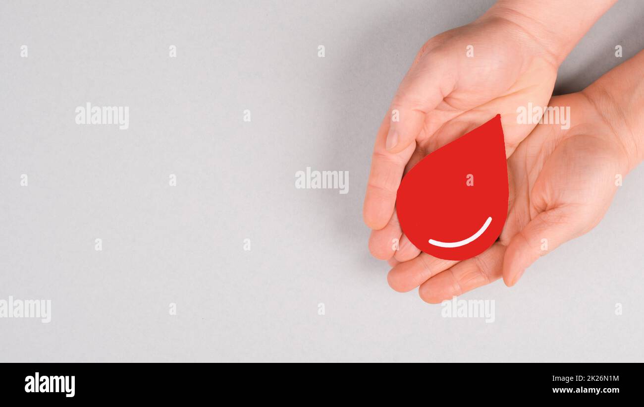 Tenere una goccia rossa nelle mani, donare il sangue, giornata mondiale dei donatori di sangue, assistenza sanitaria, trasfusione Foto Stock