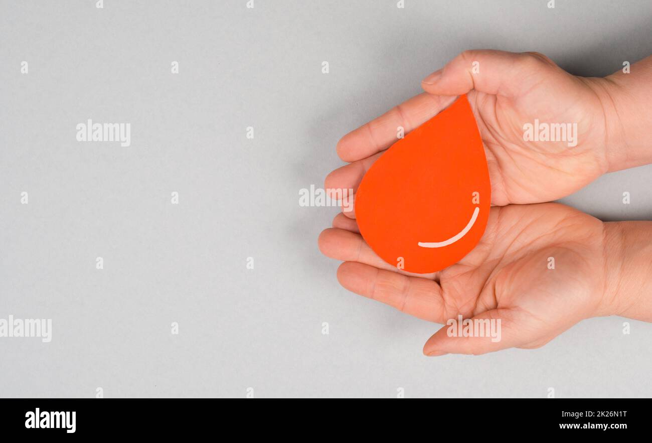Tenere una goccia rossa nelle mani, donare il sangue, giornata mondiale dei donatori di sangue, assistenza sanitaria, trasfusione Foto Stock