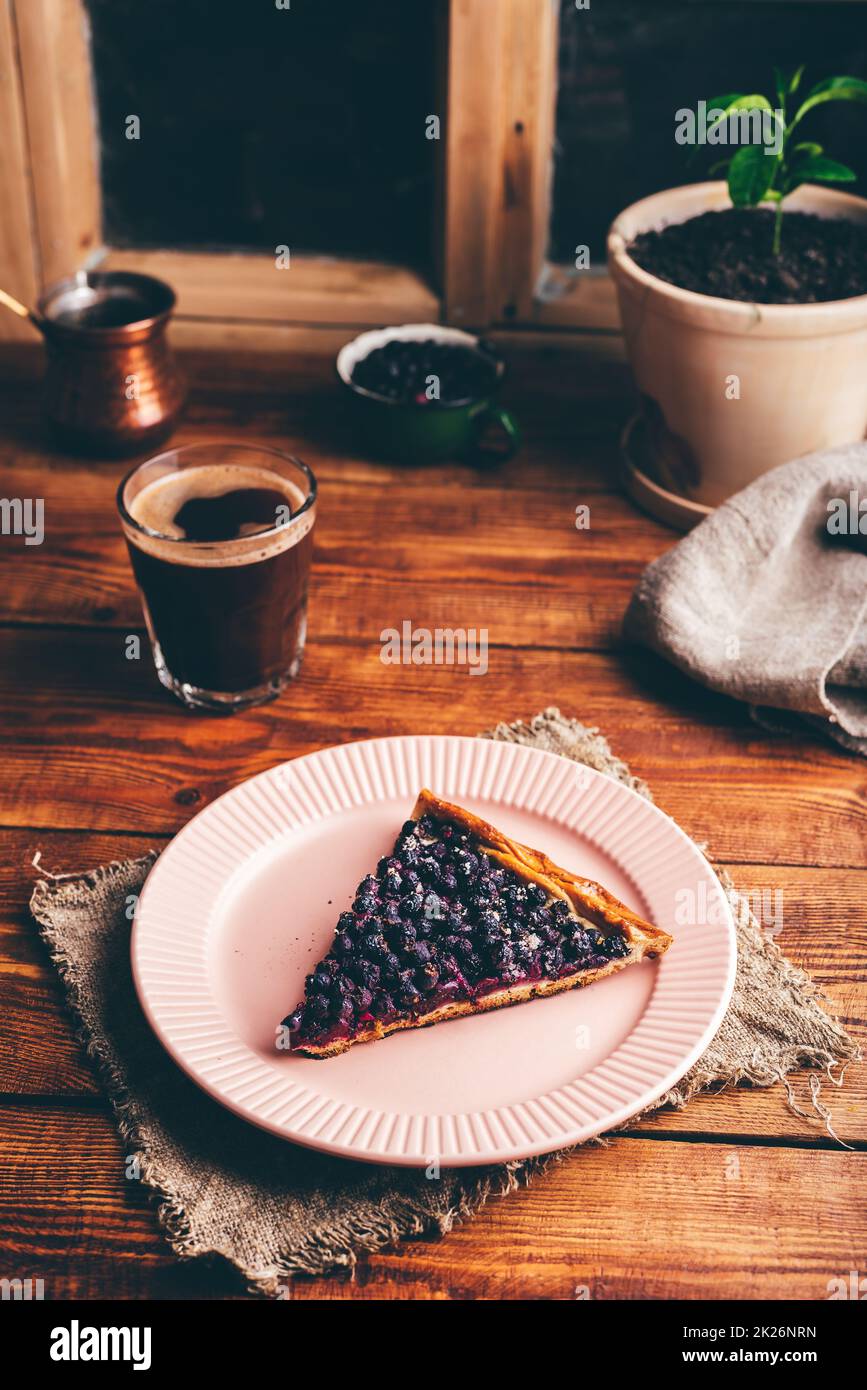 Fetta di torta di Serviceberry sul piatto e bicchiere di caffè turco Foto Stock