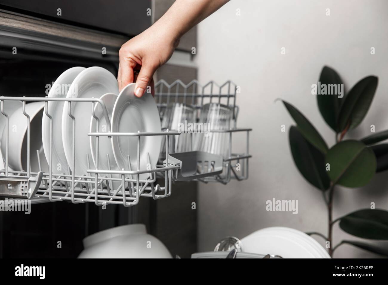 Lavastoviglie aperta con posate pulite, bicchieri, piatti all'interno della cucina casalinga Foto Stock