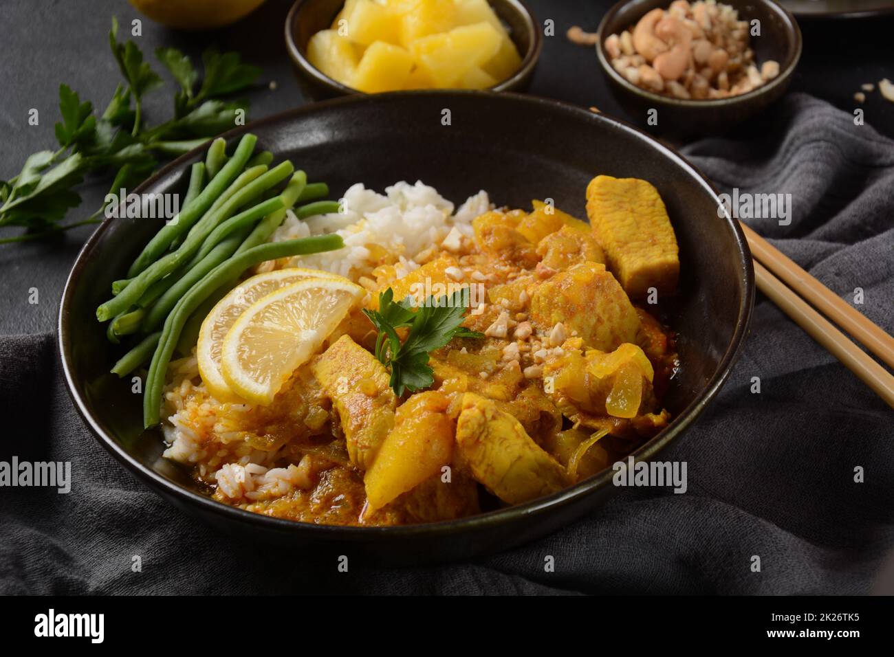 Un curry di Massaman di pollo in ciotola nera su fondo scuro. Il Massaman Curry è il miglior piatto tailandese indiano con carne di pollo, patate, cipolla e molte spezie è influenzato dalle culture musulmane malesi e thailandesi. Foto Stock