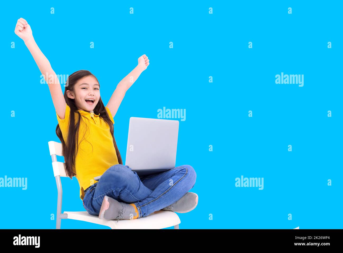 ragazza felice studente che tiene il computer portatile mentre si siede sulla sedia Foto Stock