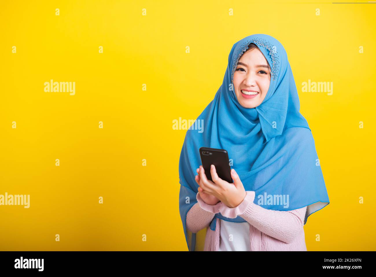 Donna araba musulmana asiatica Islam indossare hijab sorriso che utilizza tenere cellulare smartphone Foto Stock
