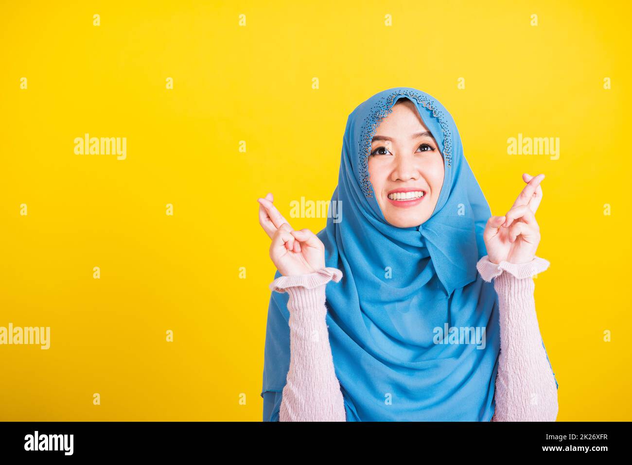 Donna indossare hijab lei sorridente e tenendo le dita incrociate per buona fortuna Foto Stock