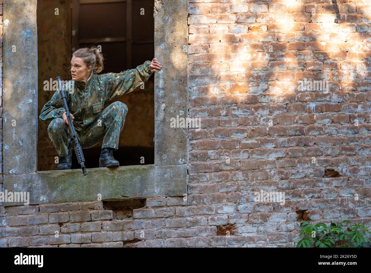 giovane donna in azione mentre si gioca paintball Foto Stock