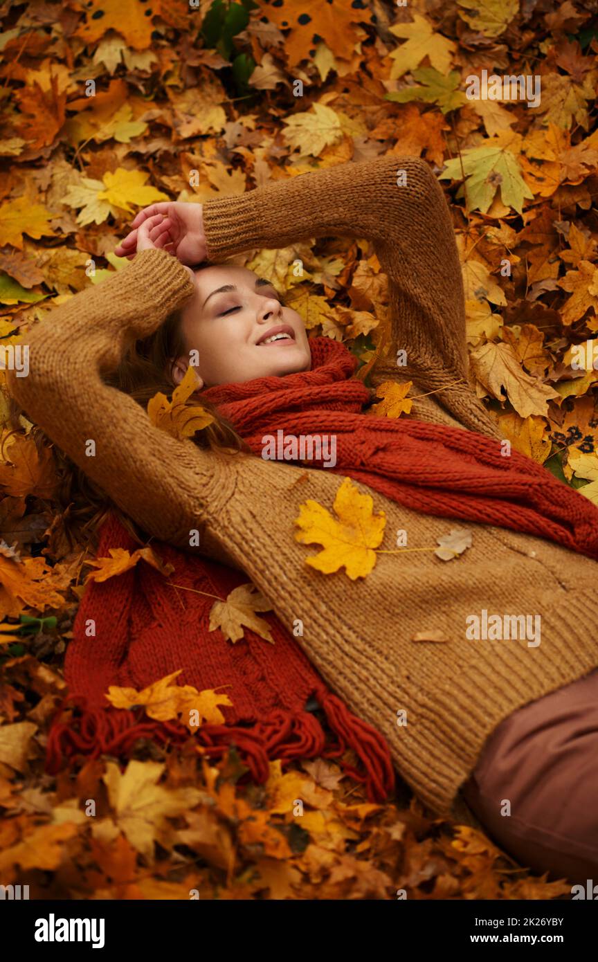 Felice bella donna sdraiata sulle foglie d'autunno Foto Stock