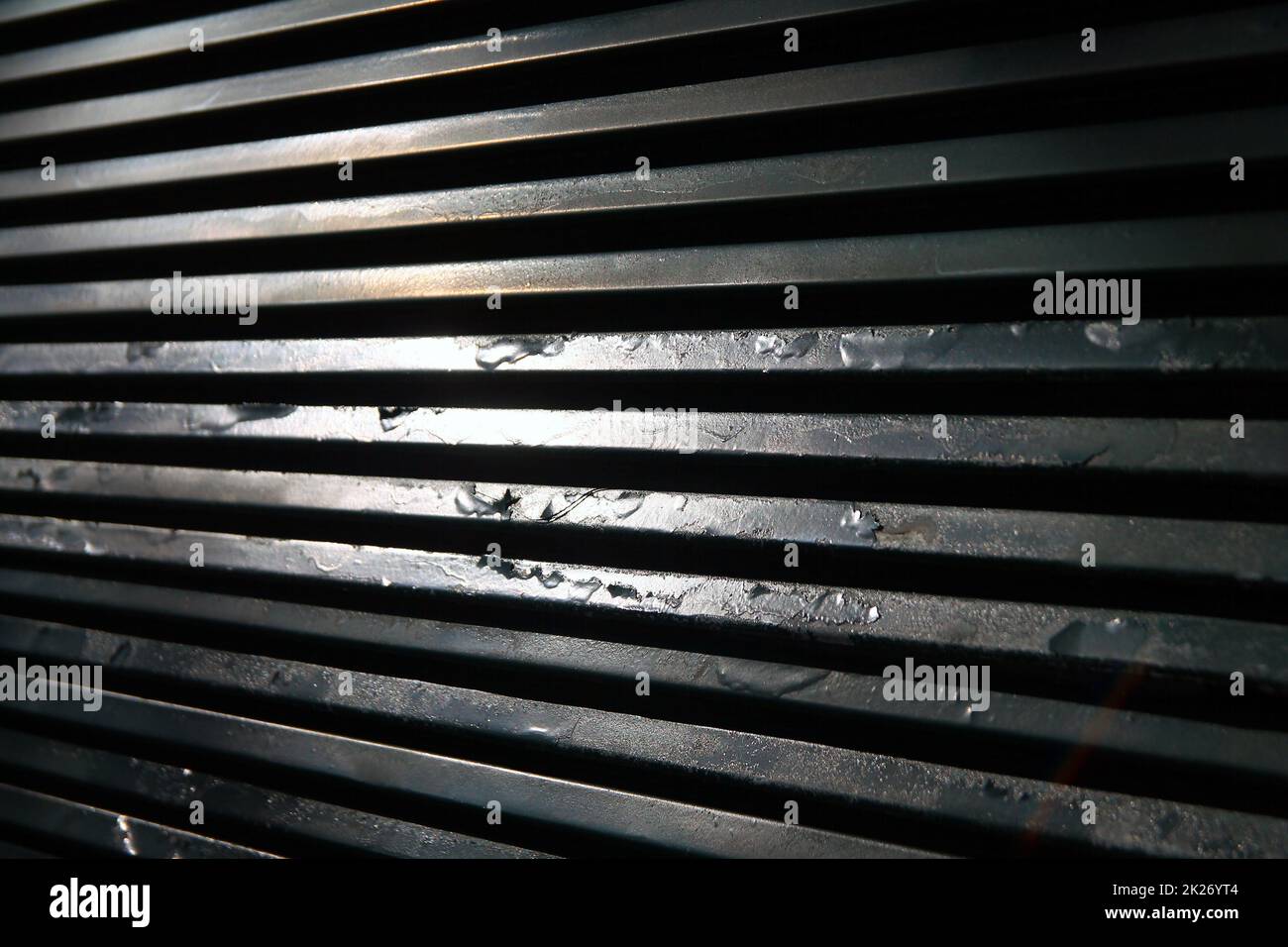 La ruggine di una vecchia griglia metallica con i riflessi del sole Foto Stock