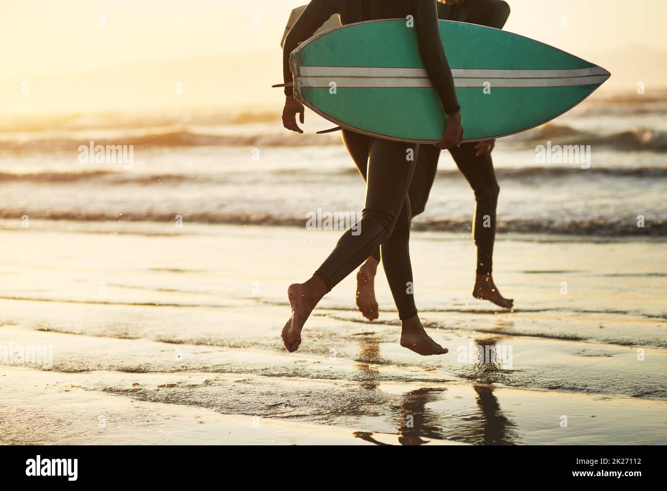 Correre nell'oceano selvaggio. Scatto di una giovane coppia irriconoscibile che va a fare surf in spiaggia. Foto Stock