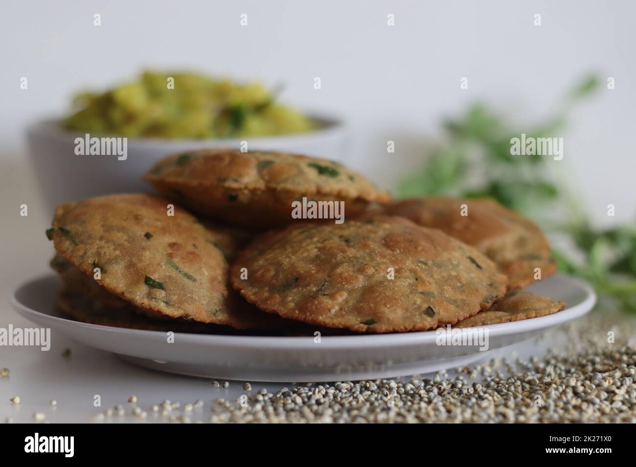 Bajra methi puri. Pane piatto indiano fritto a base di farina di miglio perla e foglie di fenugreek. Servito con purè di patate speziate con sugo di patate. Scatto su bianco b Foto Stock