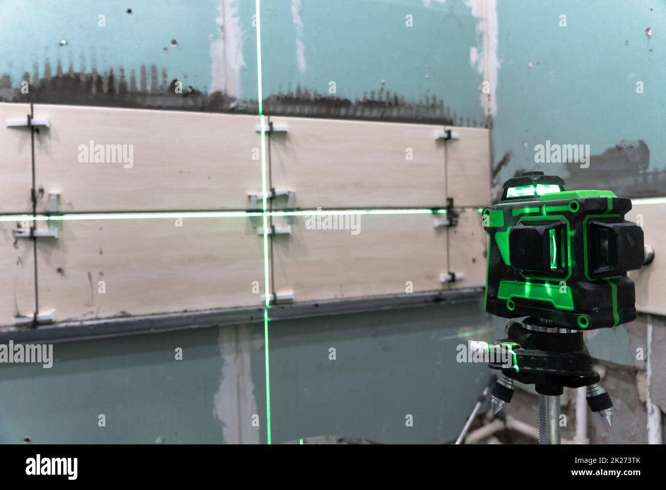 Costruzione e riparazione di pareti in un nuovo building.posing piastrelle da parete utilizzando un livello di costruzione e una livella laser. Ristrutturazione della casa. Eseguire calcoli e misurazioni utilizzando un laser Foto Stock