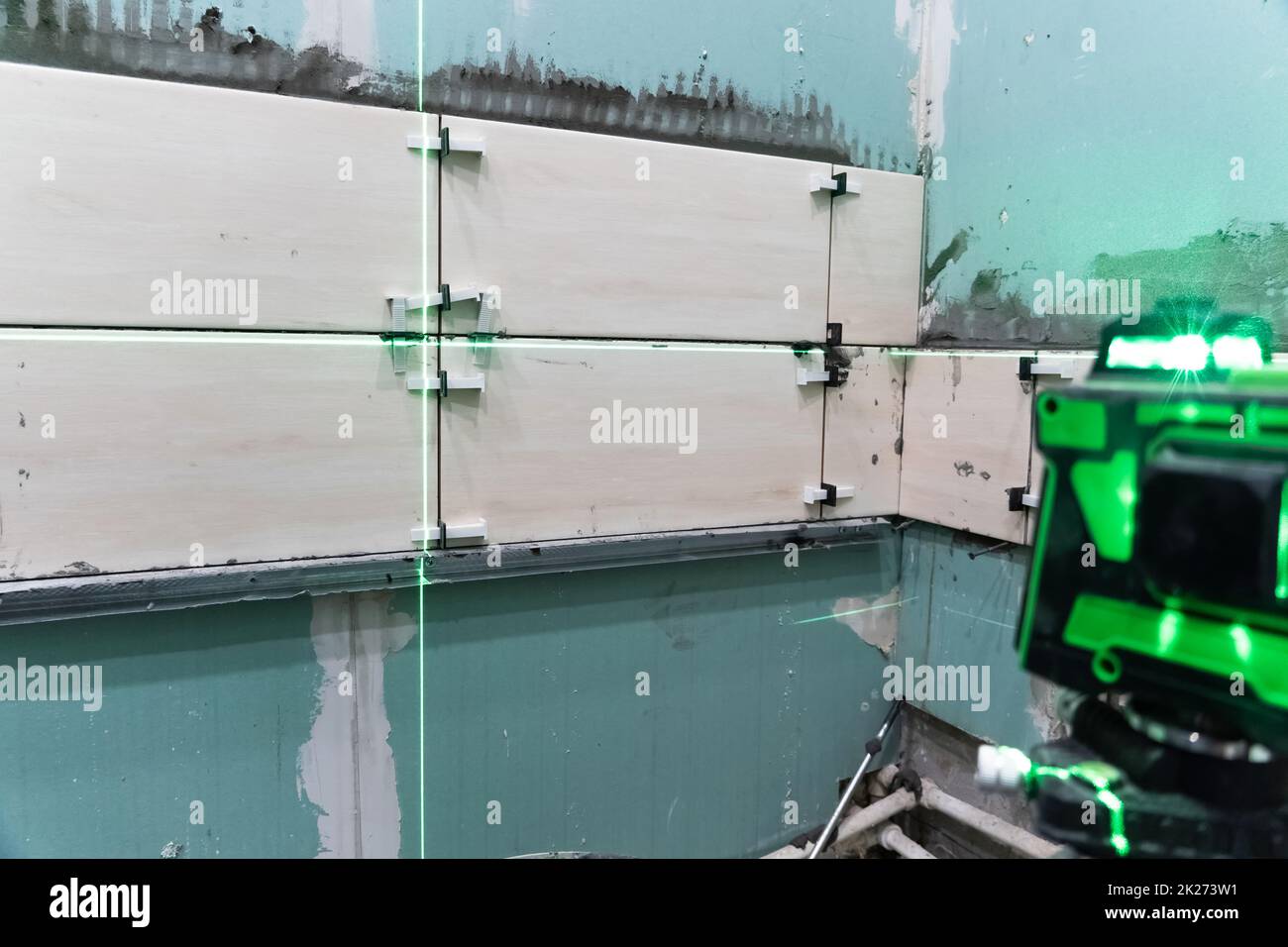 Costruzione e riparazione di pareti in un nuovo building.posing piastrelle da parete utilizzando un livello di costruzione e una livella laser. Ristrutturazione della casa. Eseguire calcoli e misurazioni utilizzando un laser Foto Stock
